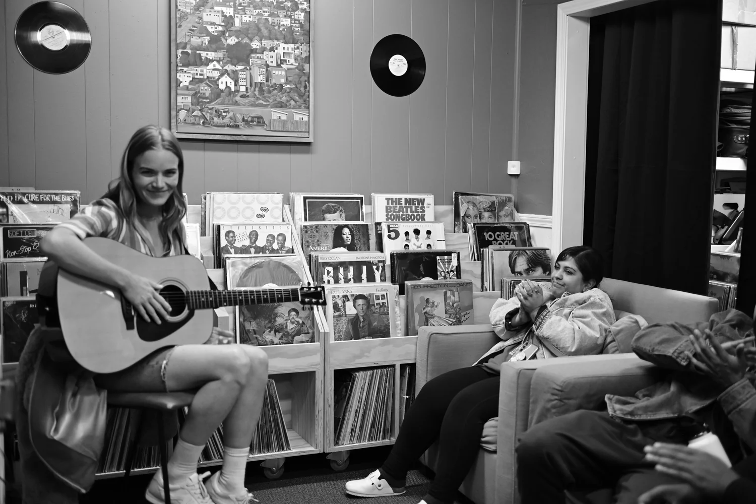 Black-and-white photo of a guitarist performing for seated listeners.