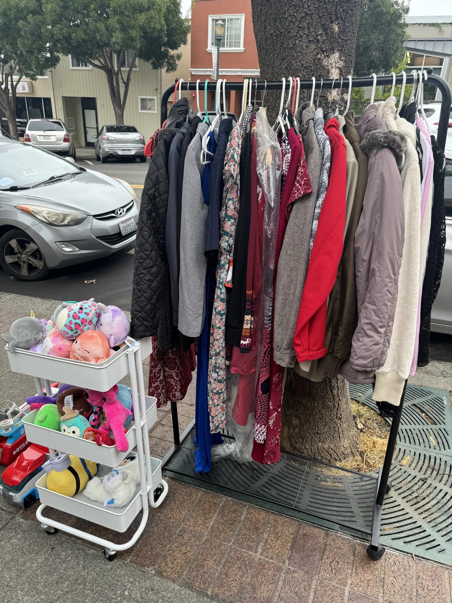 Clothing and accessories displayed on sidewalk racks.