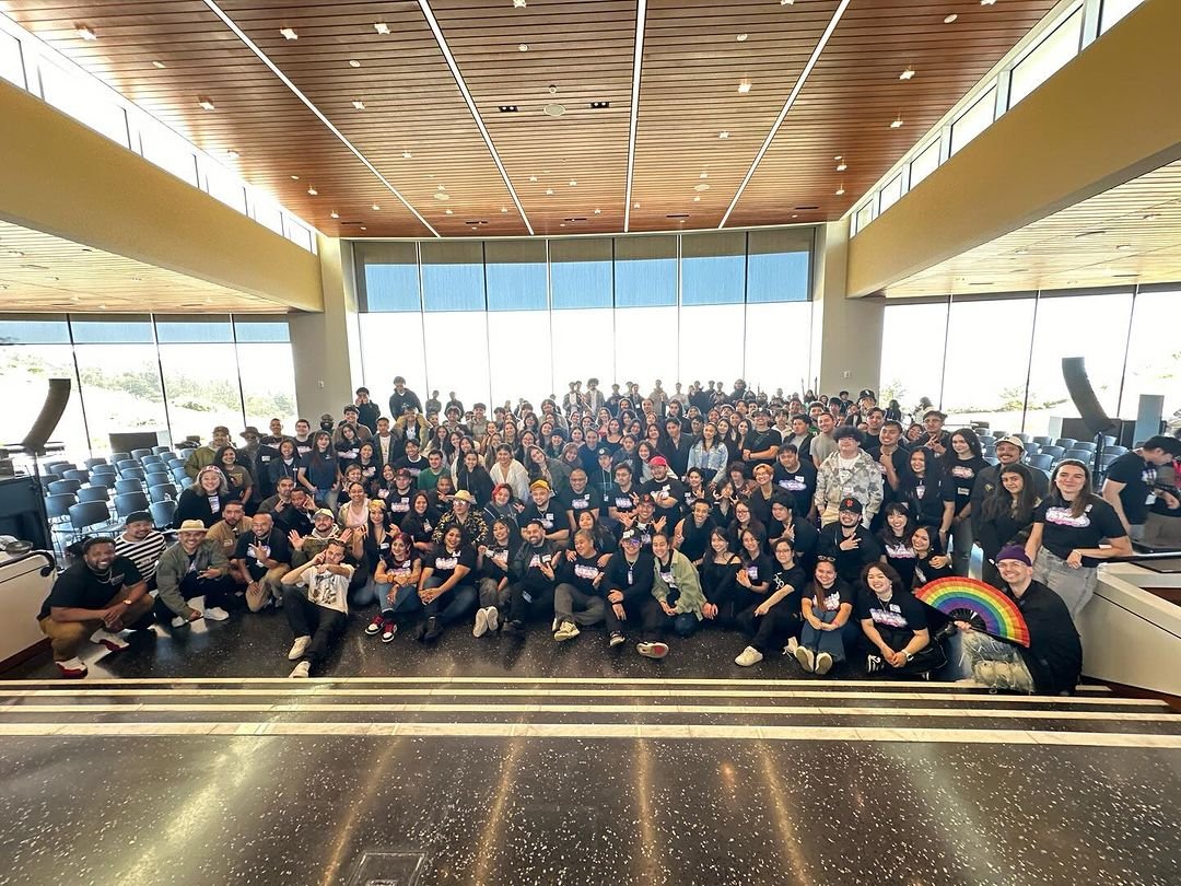 Large group portrait in a bright auditorium.