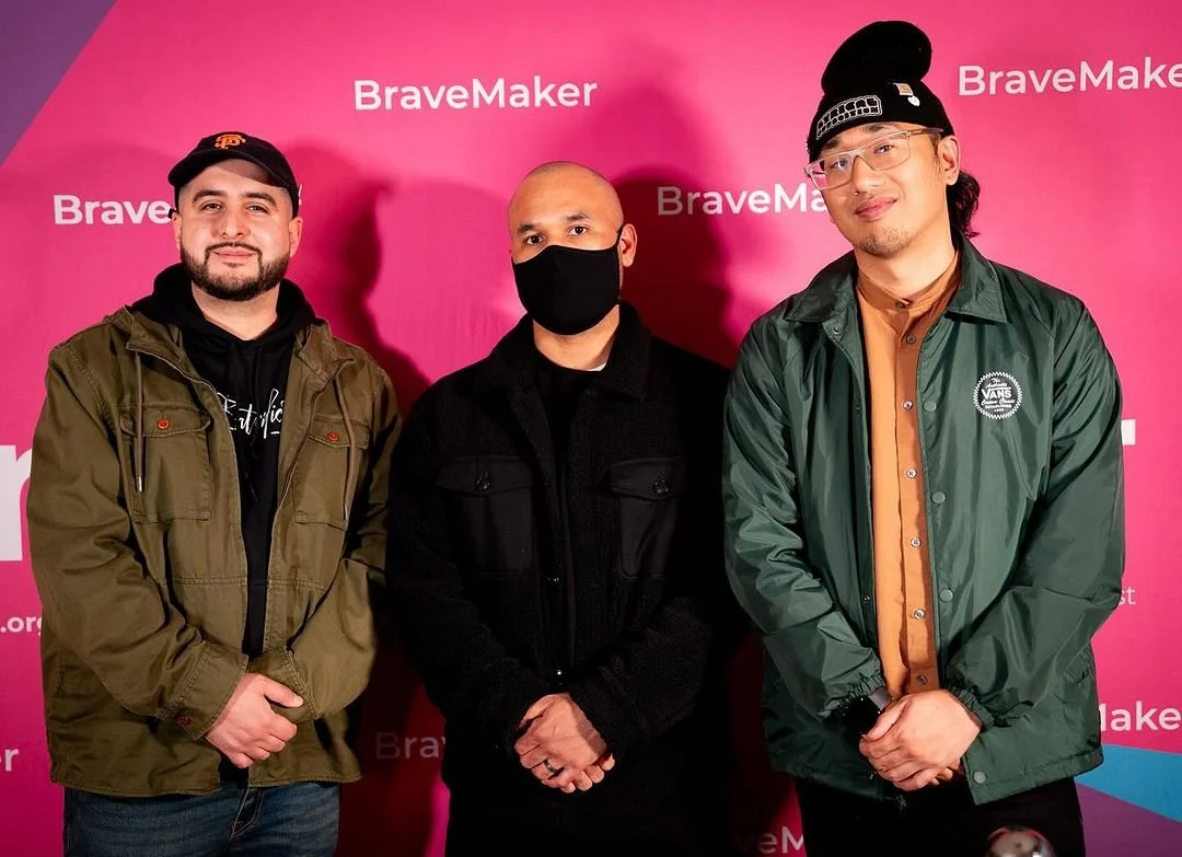 Three guests pose against the BraveMaker backdrop.