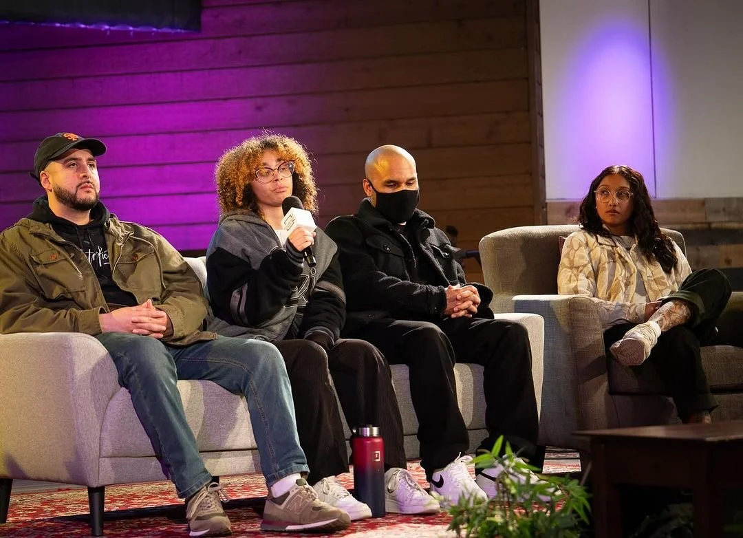 Four panelists seated together onstage.