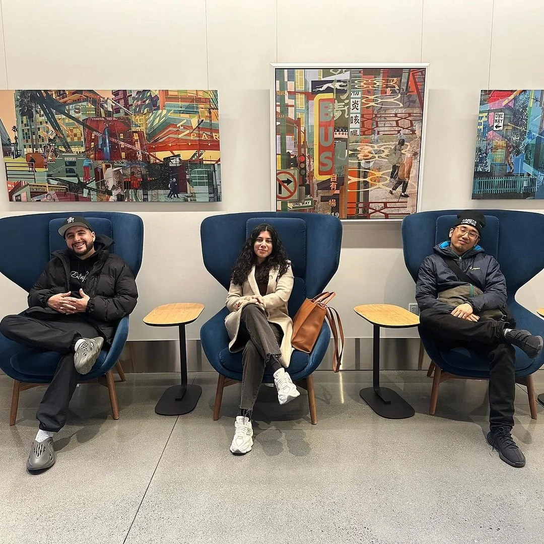 Three participants sit beneath colorful artwork.