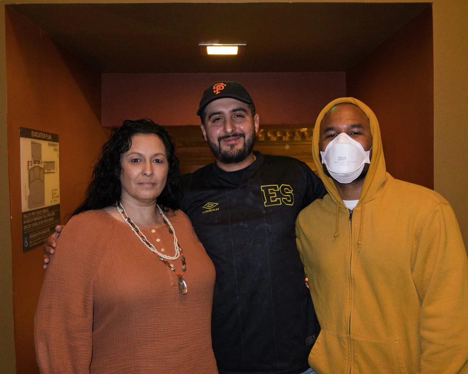 Three attendees posing together in a theater hallway.