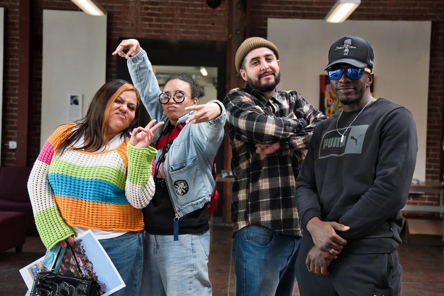 Four participants posing playfully in front of a brick wall.
