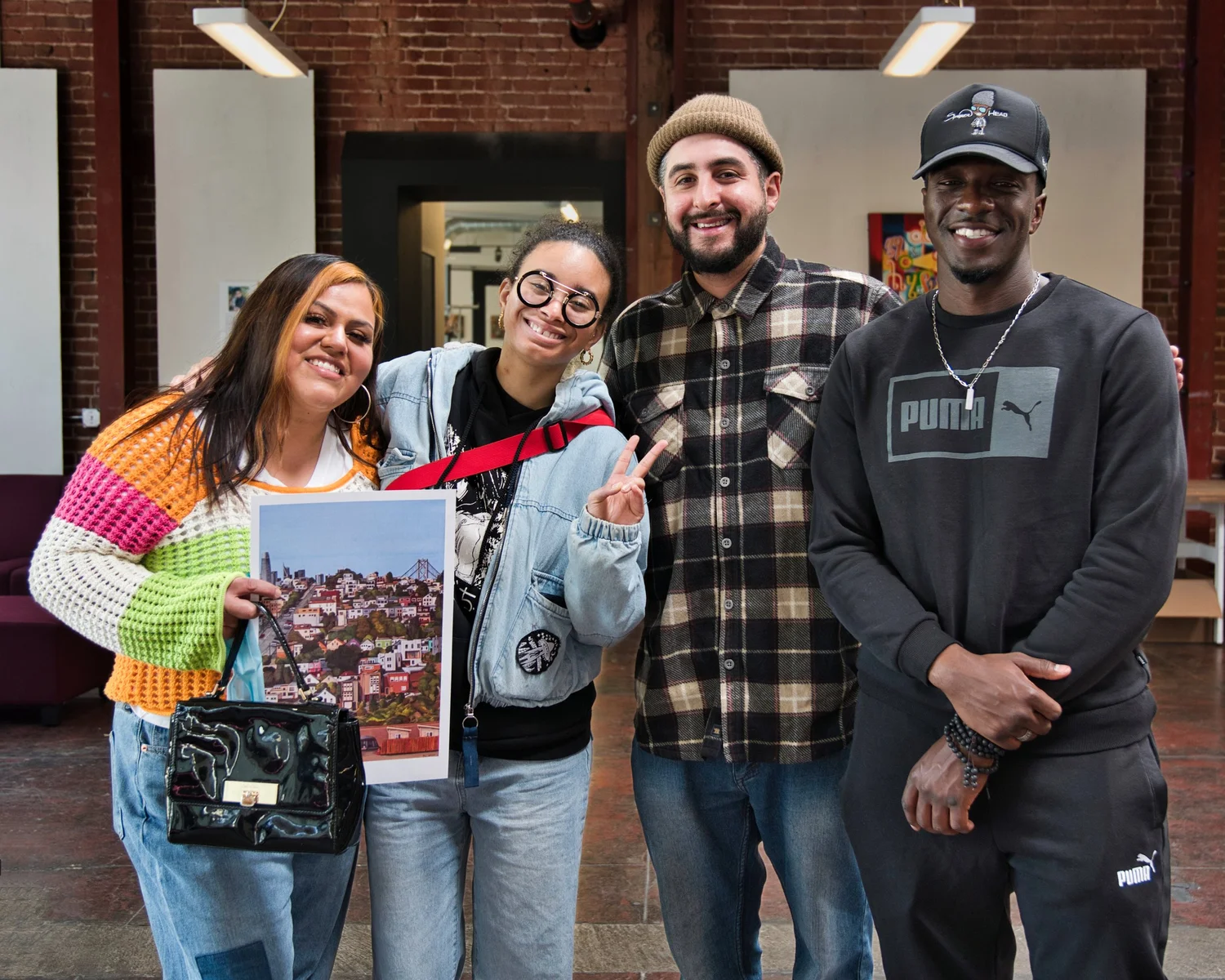 Four participants posing together, one holding artwork.