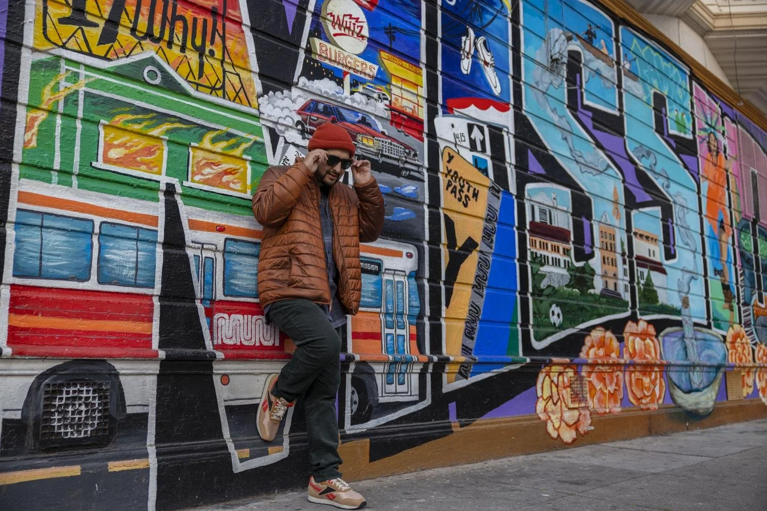 Fego leans against a mural painted by Precita Eyes, “This mural is my life! Muni passes, playing soccer and Mission Dolores high school. It’s all here,” said Fego. ( Emily Curiel )