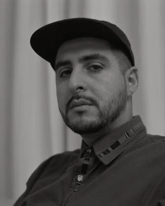 Black-and-white portrait of a person wearing a cap.