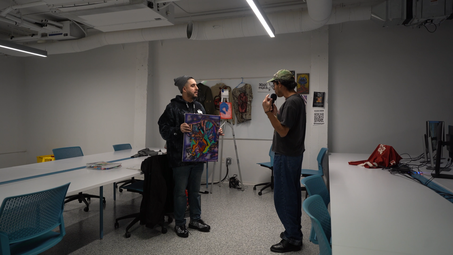 A guest speaks with a presenter near the artwork.