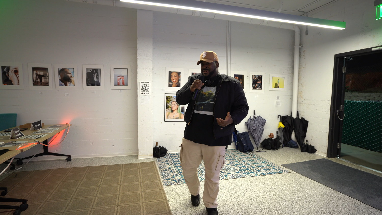 A vocalist performs among photographs in a gallery.