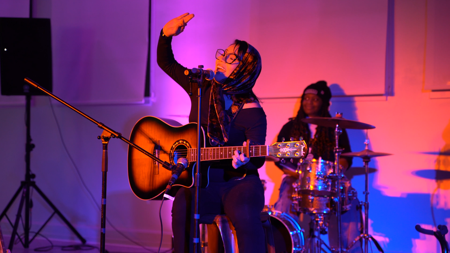 A guitarist raises one hand while singing.