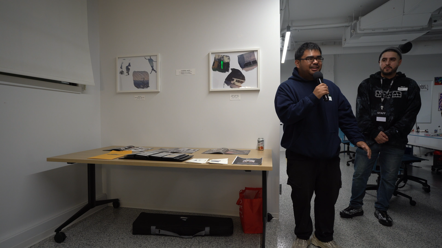 Two presenters introduce work displayed on the gallery wall.