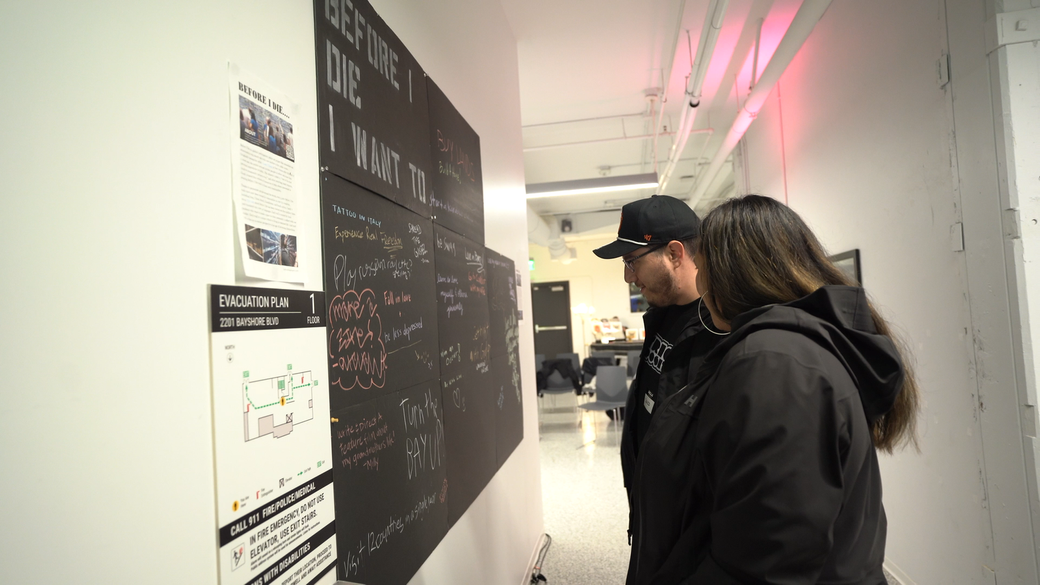 A visitor reads the Before I Die participatory wall.