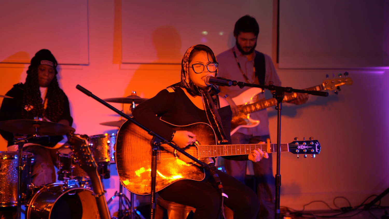 Close view of an acoustic guitarist with the band behind.