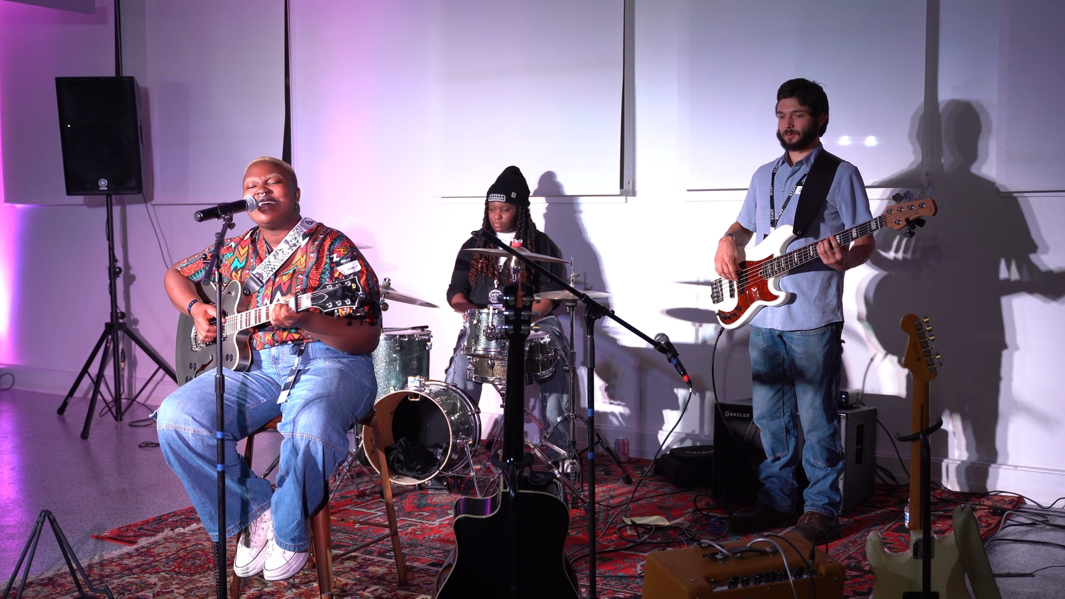 An electric guitarist performs with drums and bass.