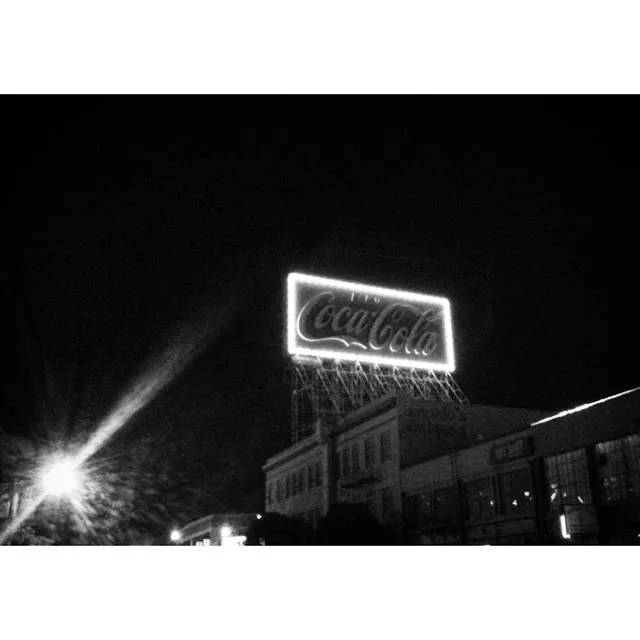 An illuminated Coca-Cola sign photographed at night.