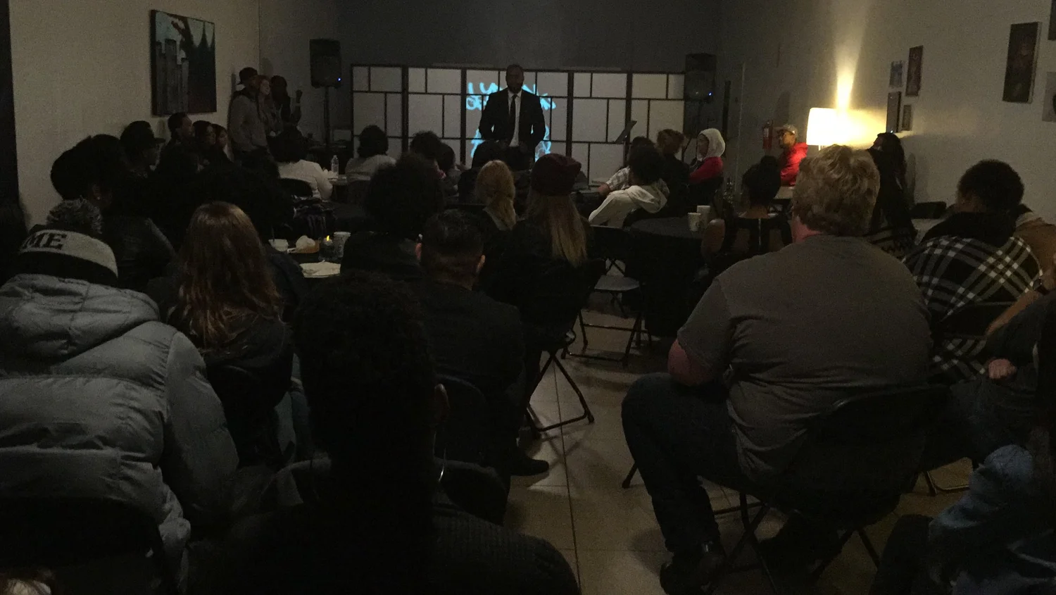 A seated audience watches the open-mic stage.
