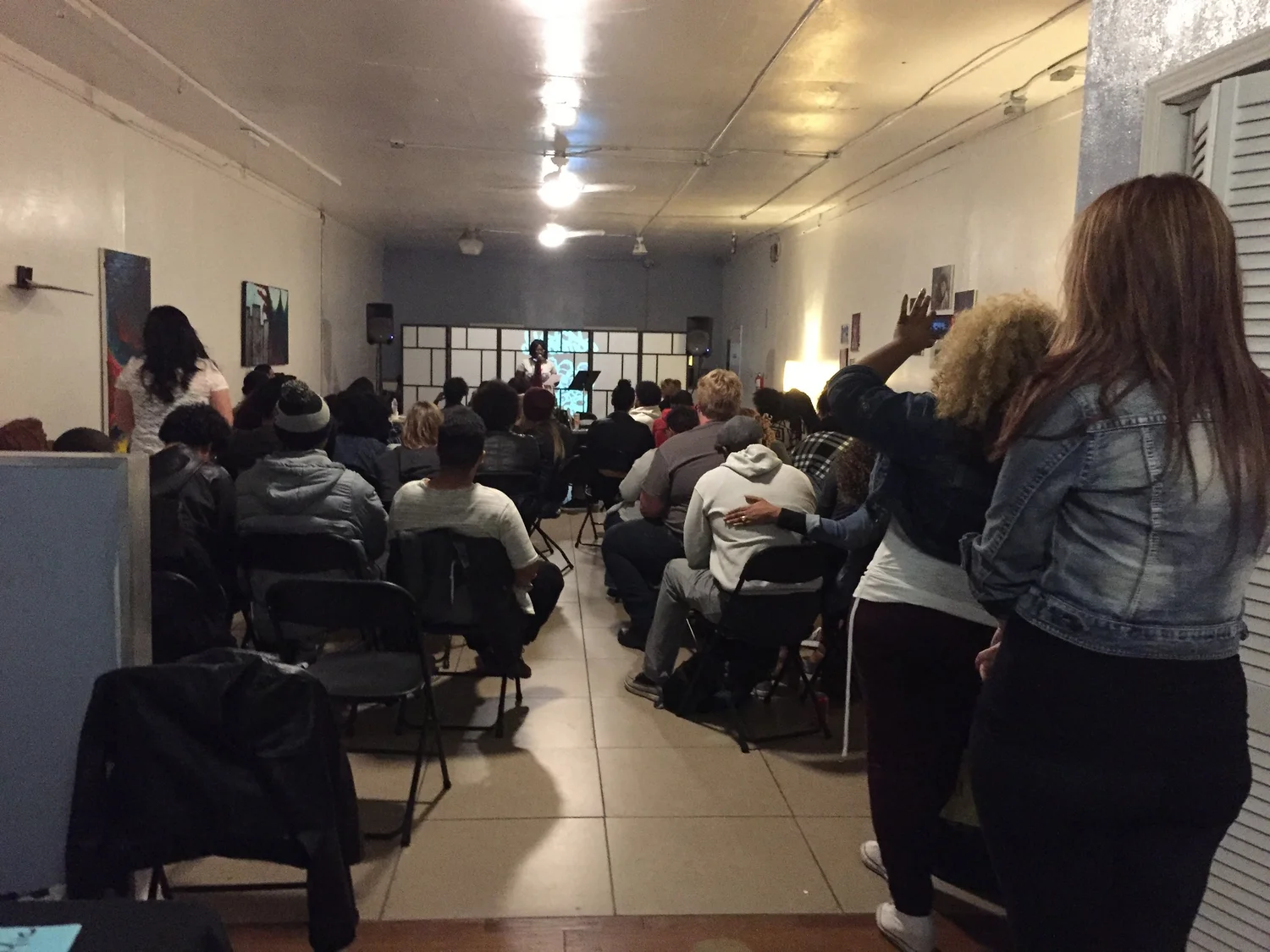 A visitor stands beside rows of seated audience members.