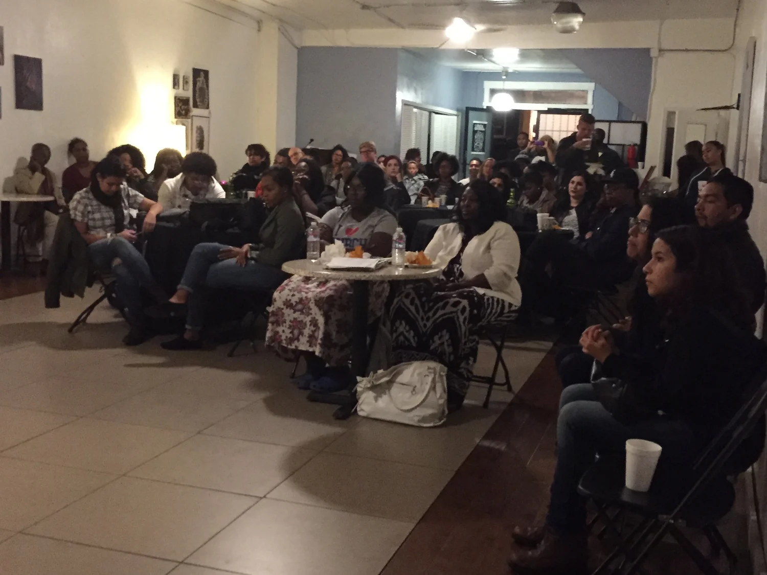 Audience members seated around tables at the open mic.