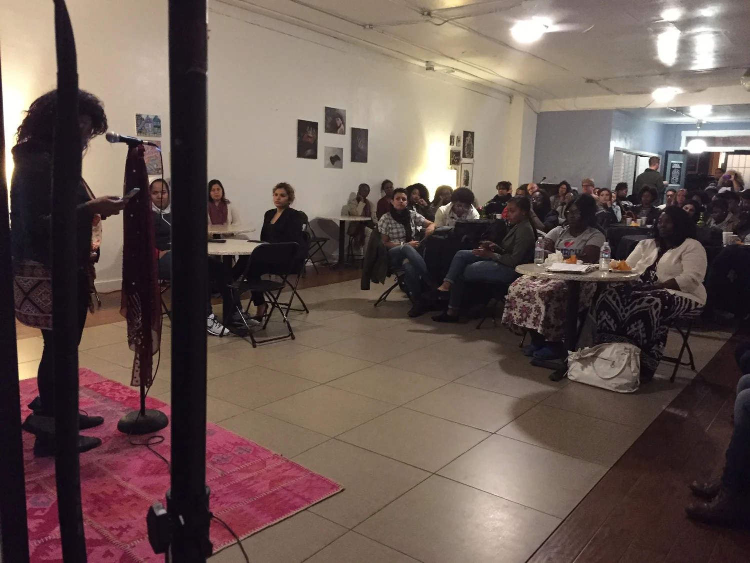 Audience members seated around tables at the open mic.
