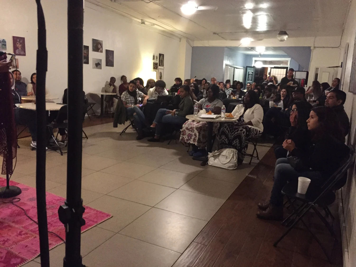 Audience members seated around tables at the open mic.