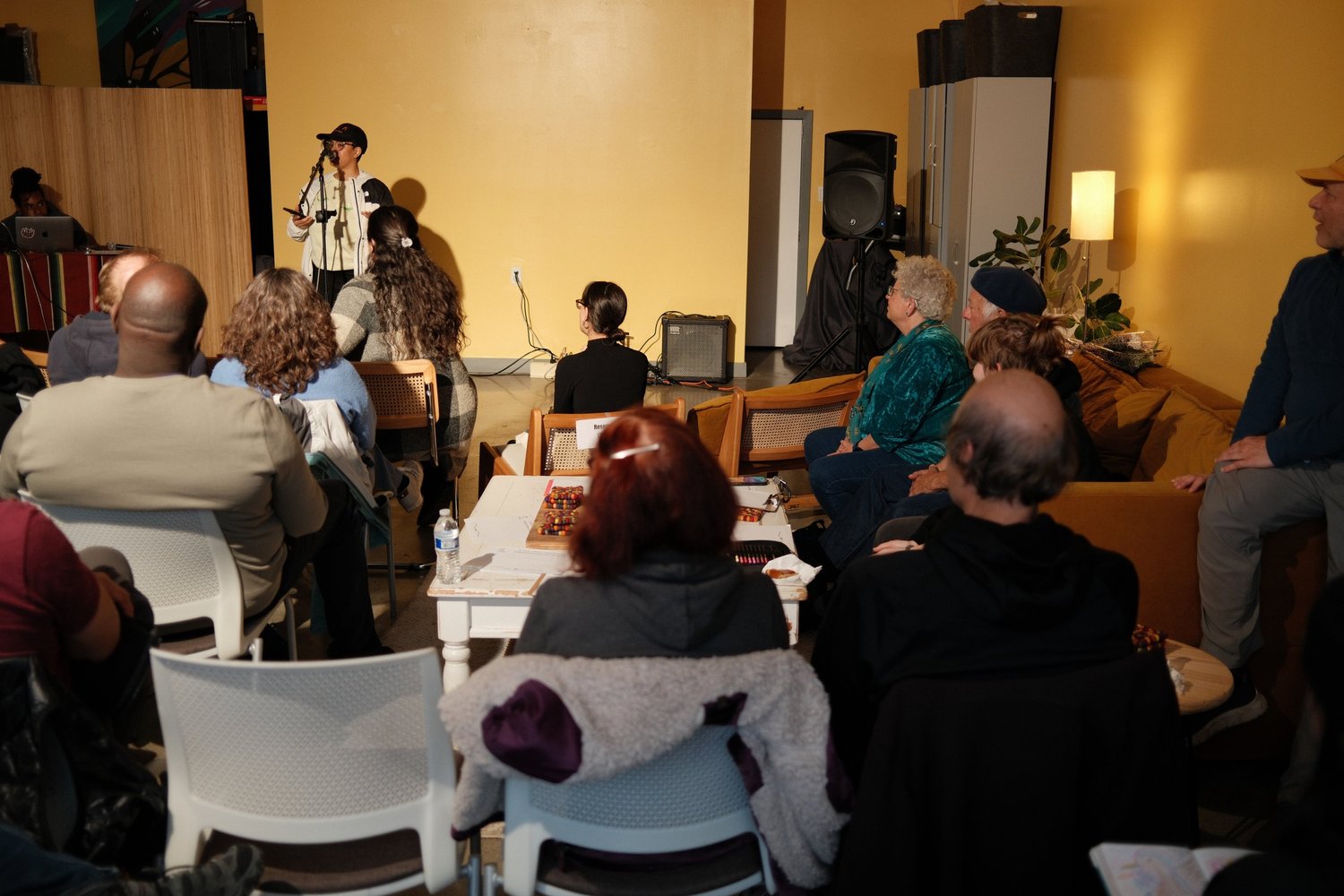 Performer addressing a closely seated audience.