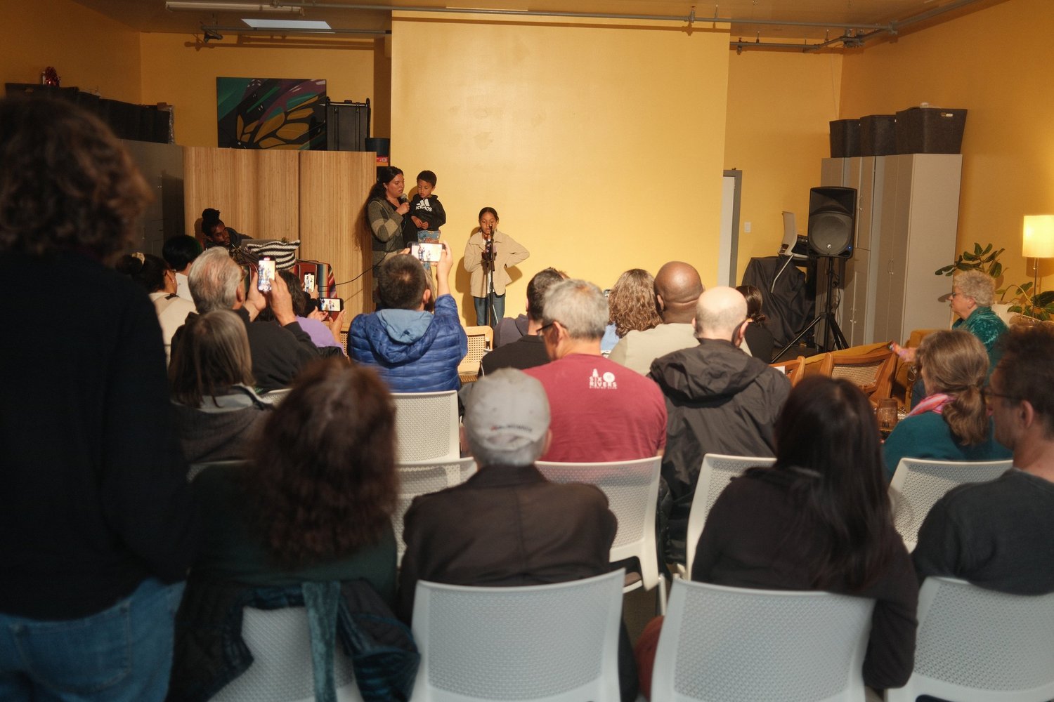 View from the back of the room toward open-mic participants.