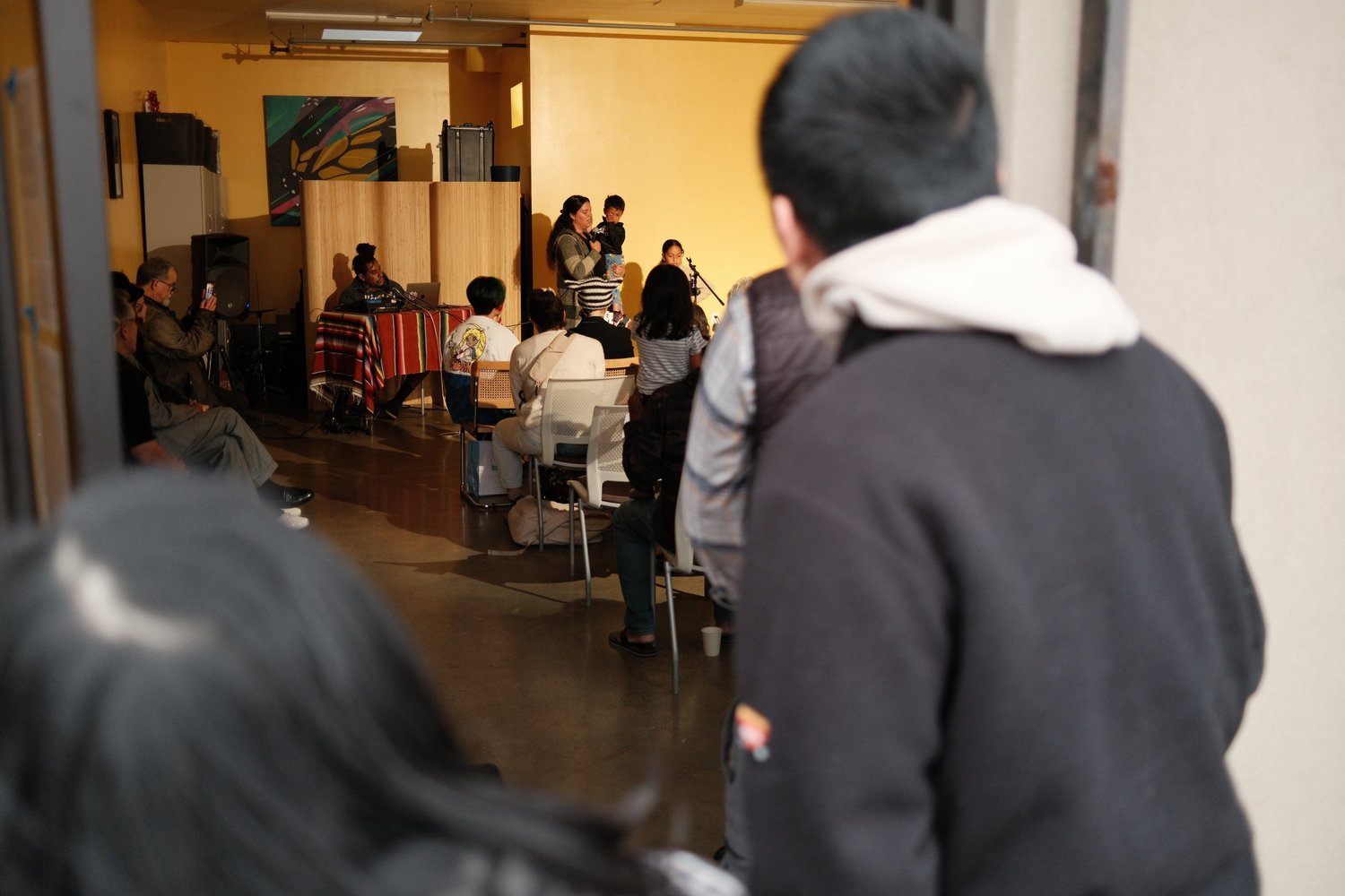 Guests entering the room while the open mic continues.
