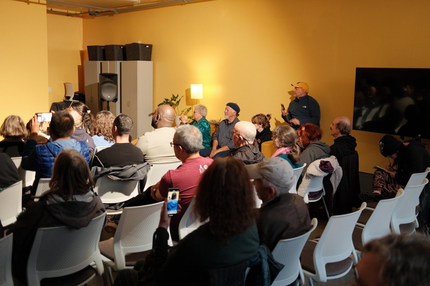 View across seated listeners toward a standing attendee.