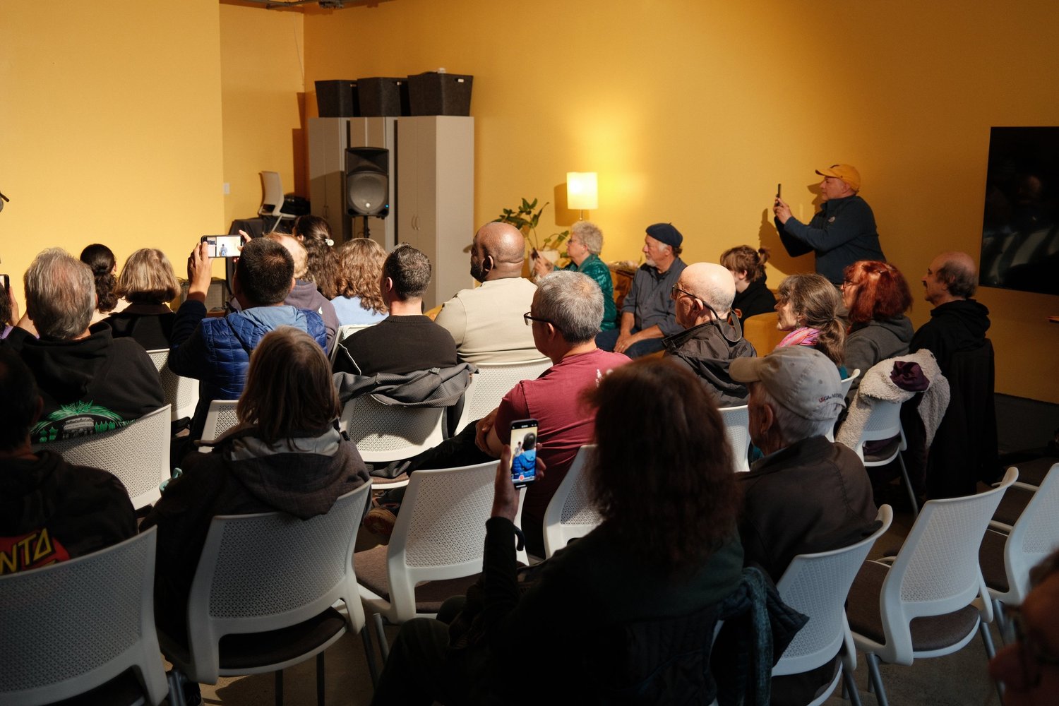 Attendee standing along the side wall during the open mic.