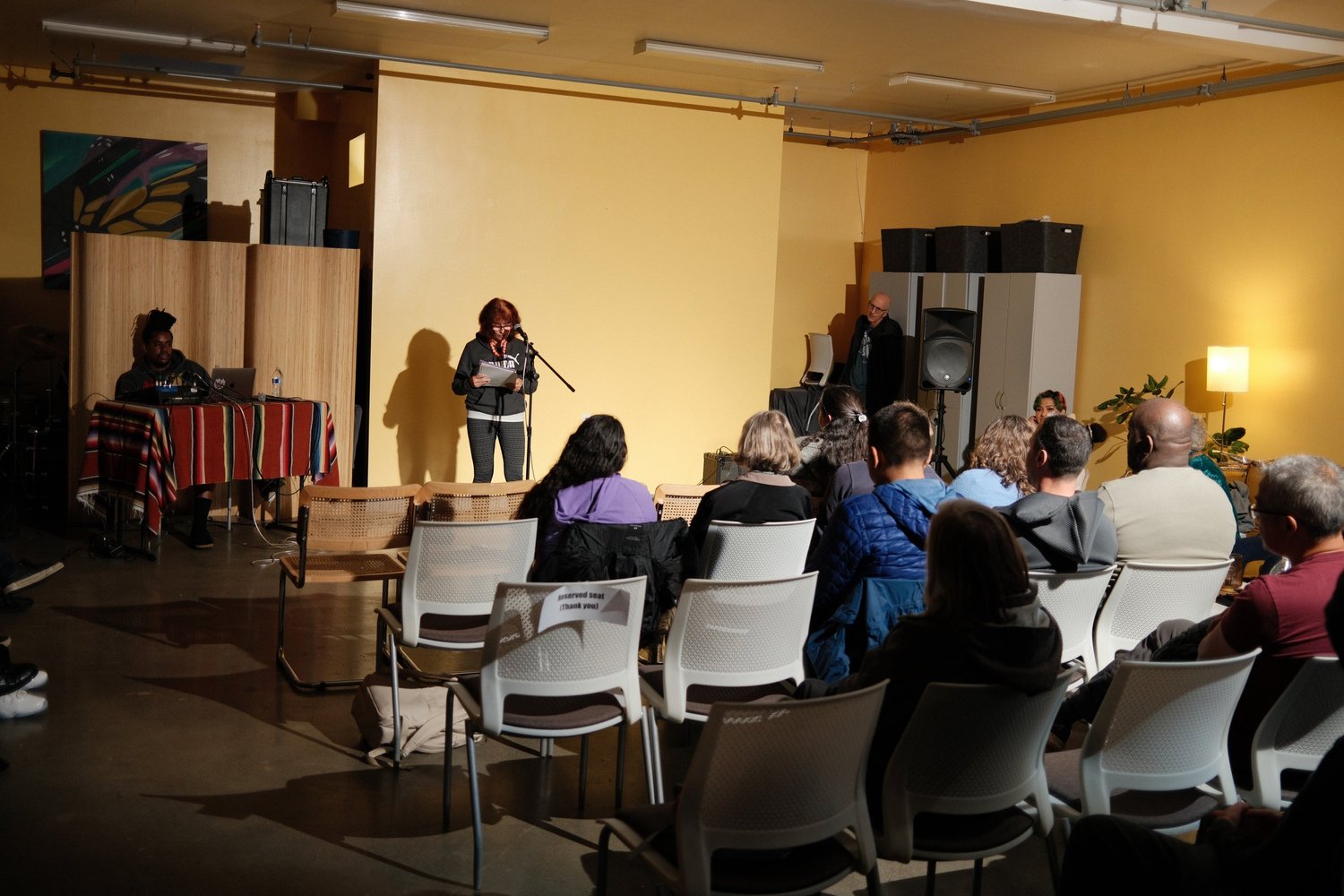 Vocalist performing at the front of the yellow-walled room.