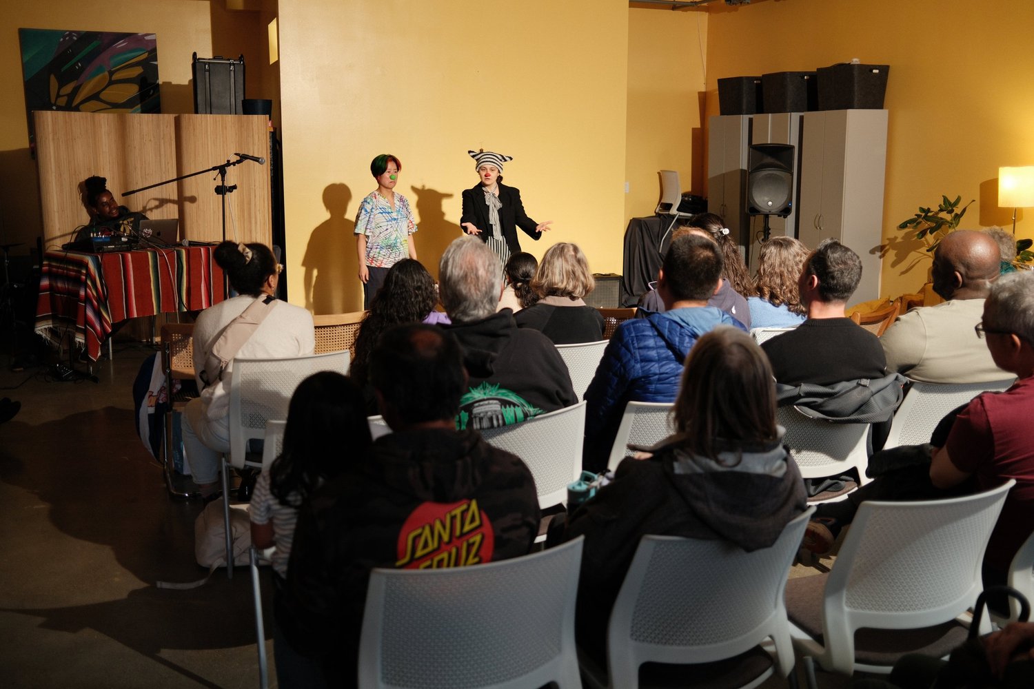 Presenter gesturing in front of a yellow wall.