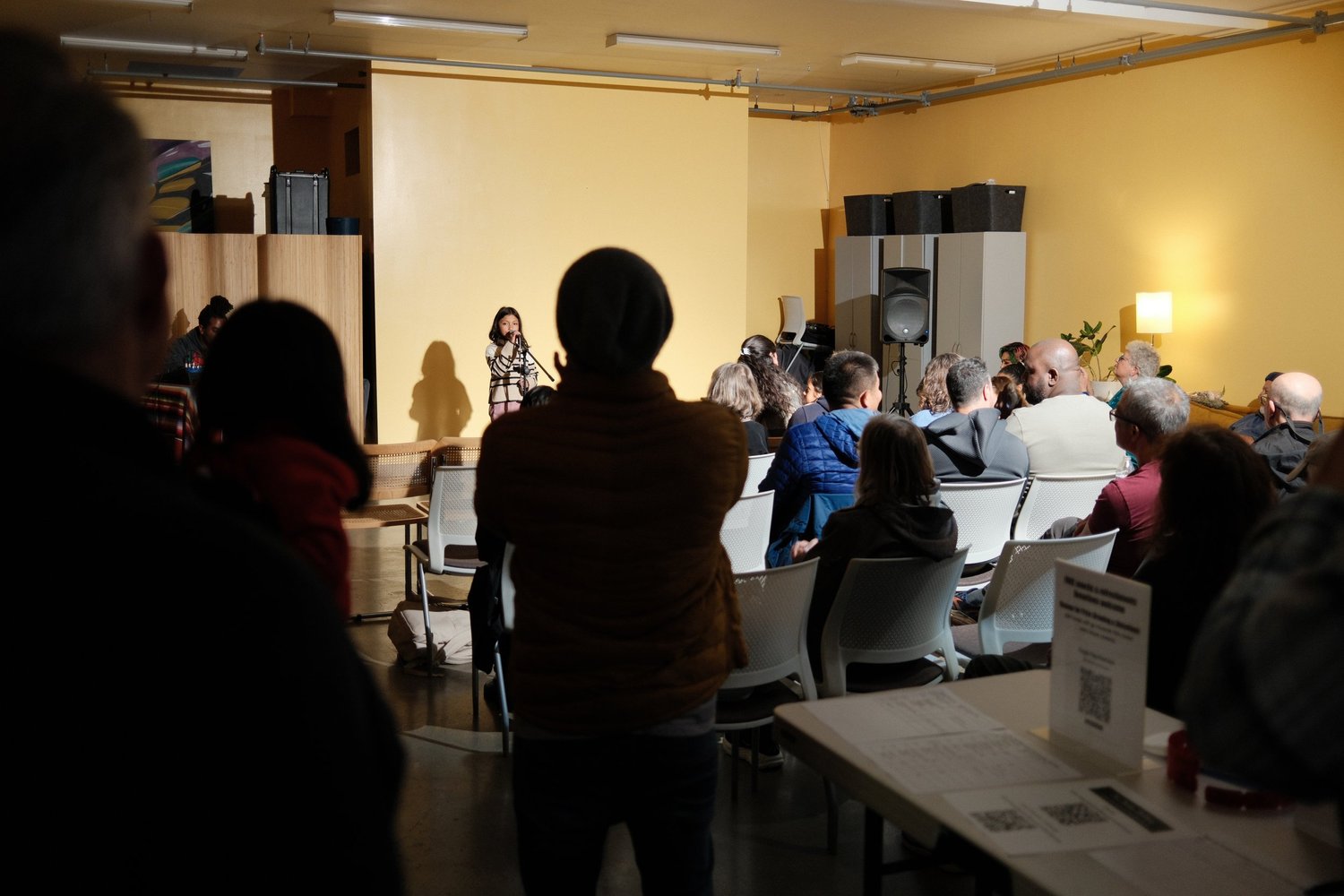 Standing attendee silhouetted in front of the seated audience.