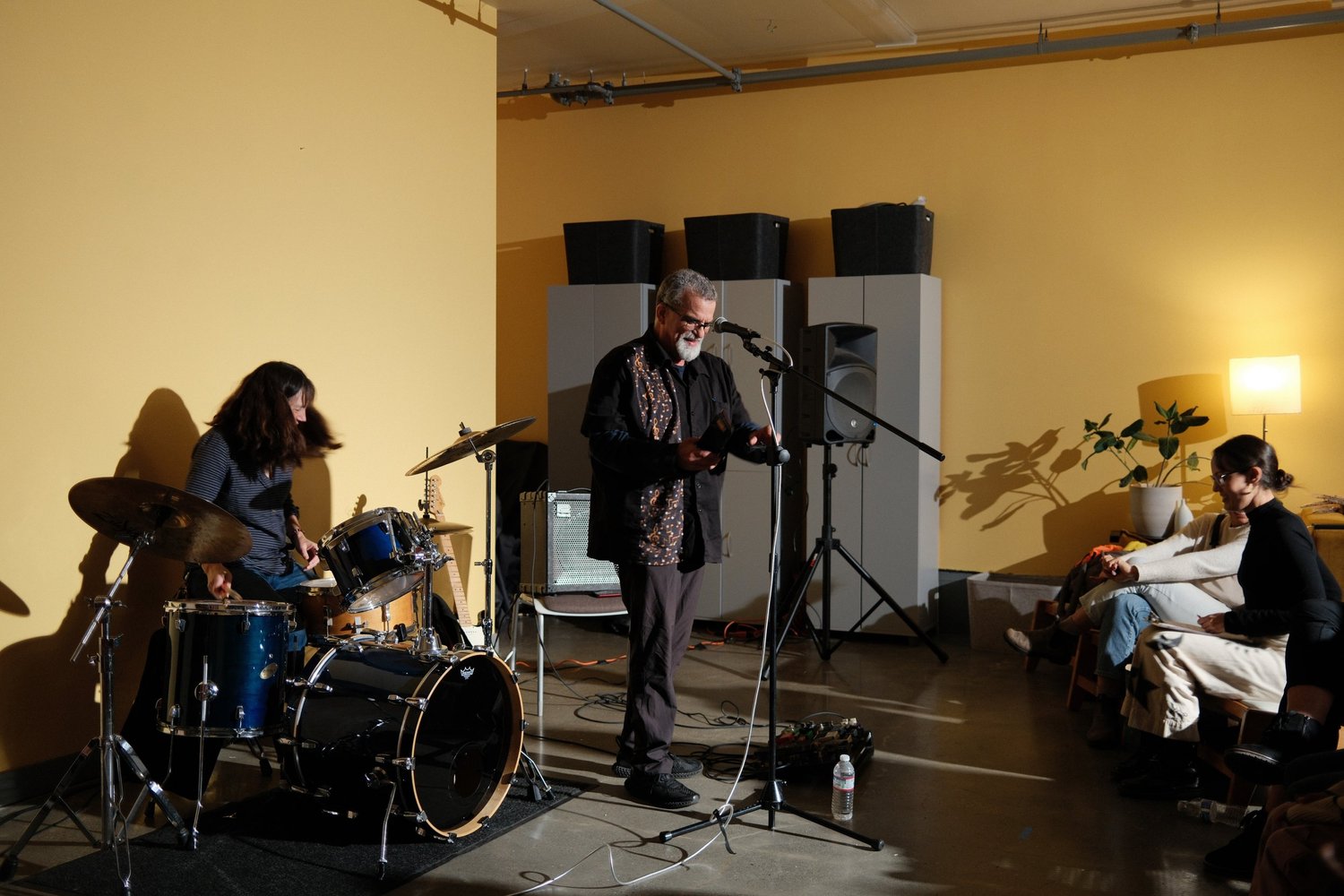 Drummer playing beside a singing guitarist.