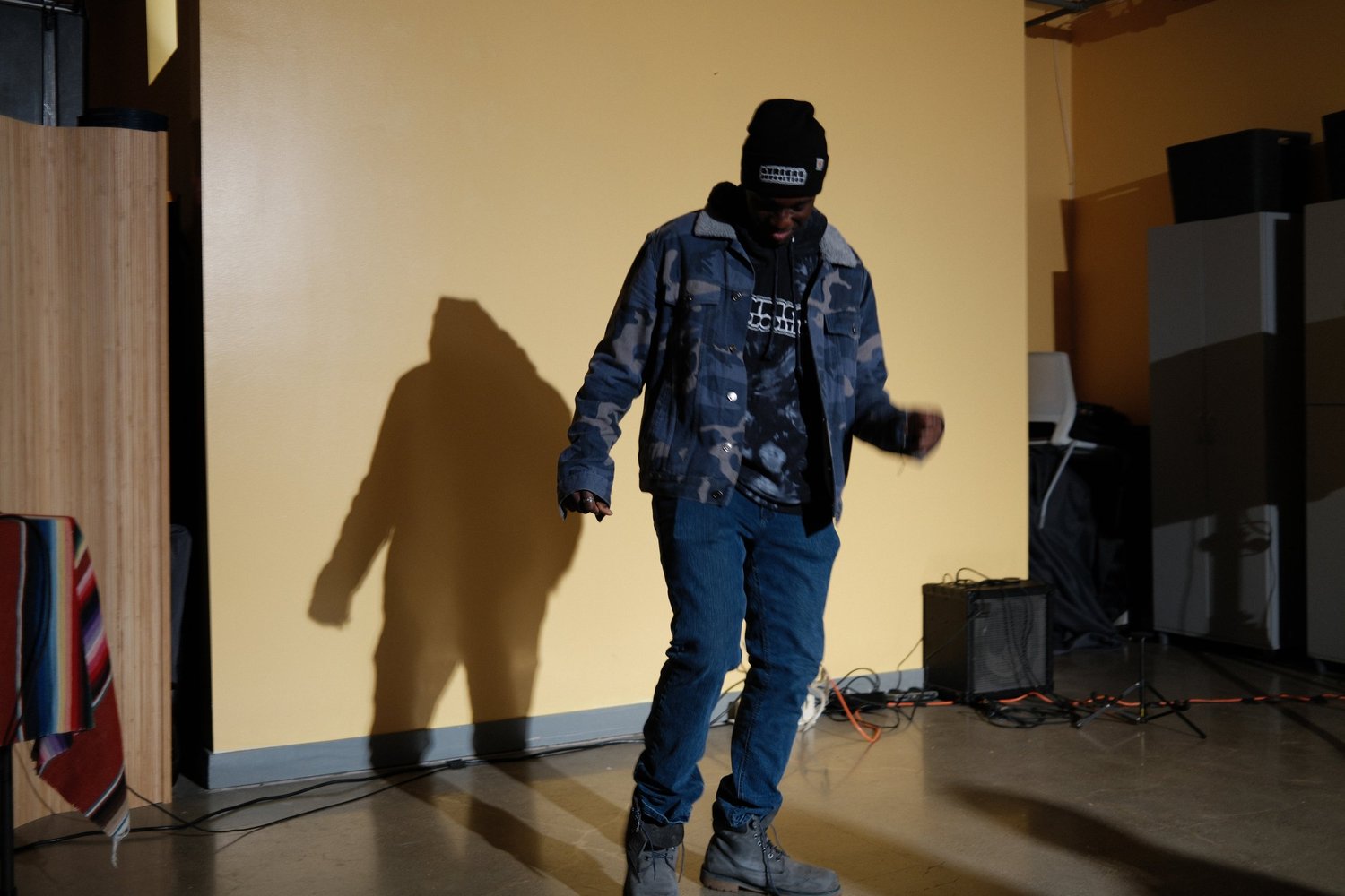 Performer in a denim jacket and beanie looking downward.