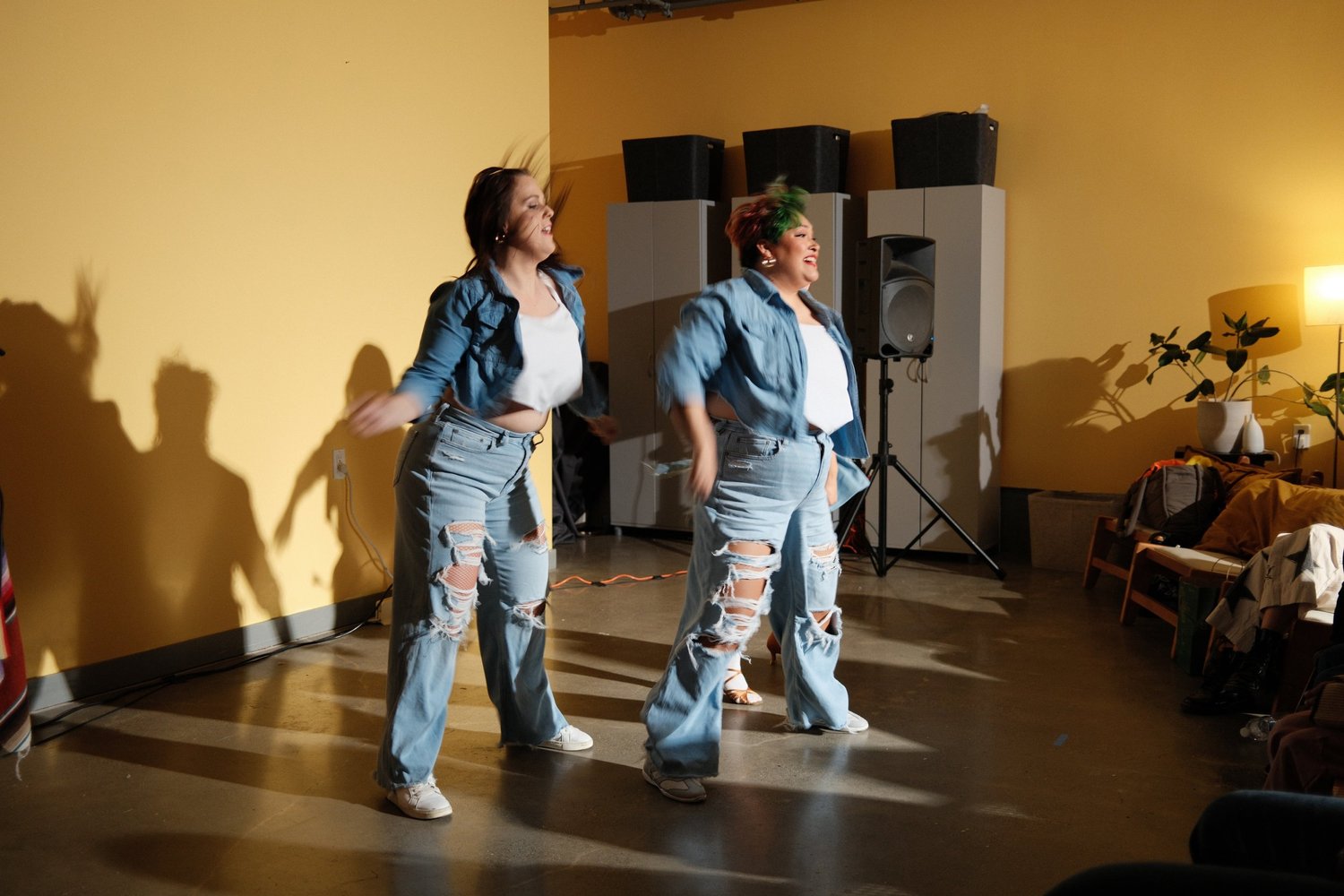 Dancers moving in front of the yellow wall.