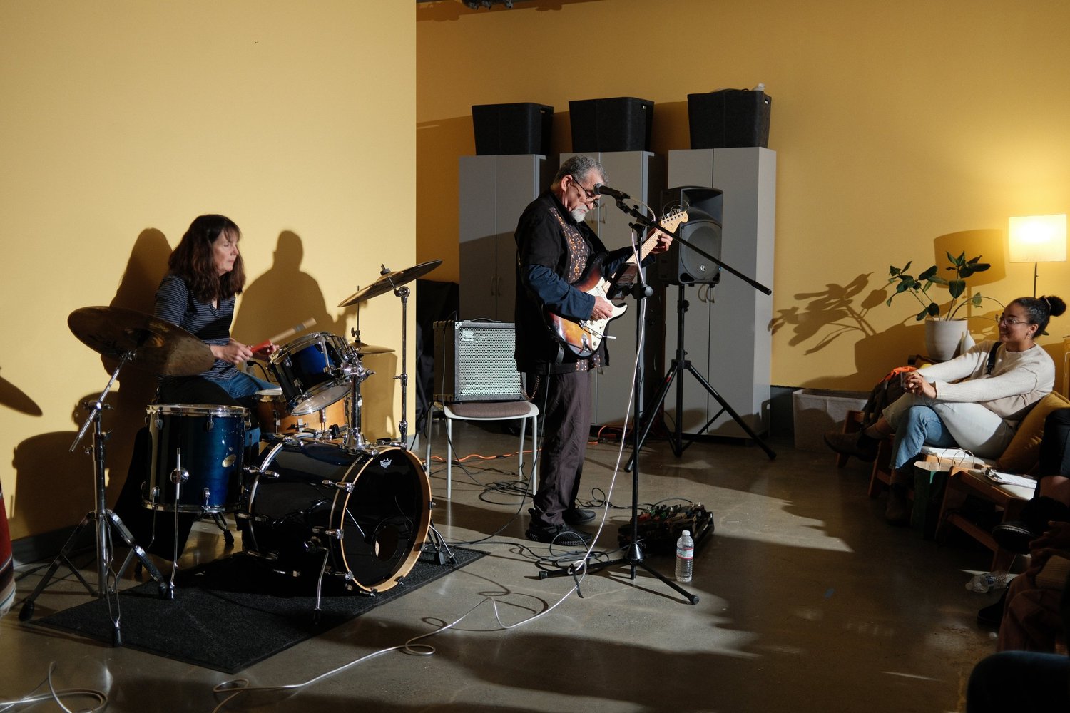 Side view of a guitarist and drummer during the open mic.