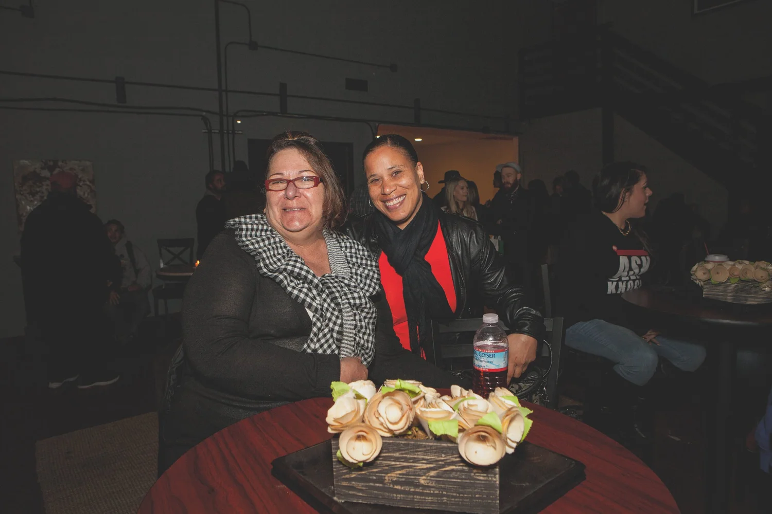 Two attendees posing beside a table with flowers.
