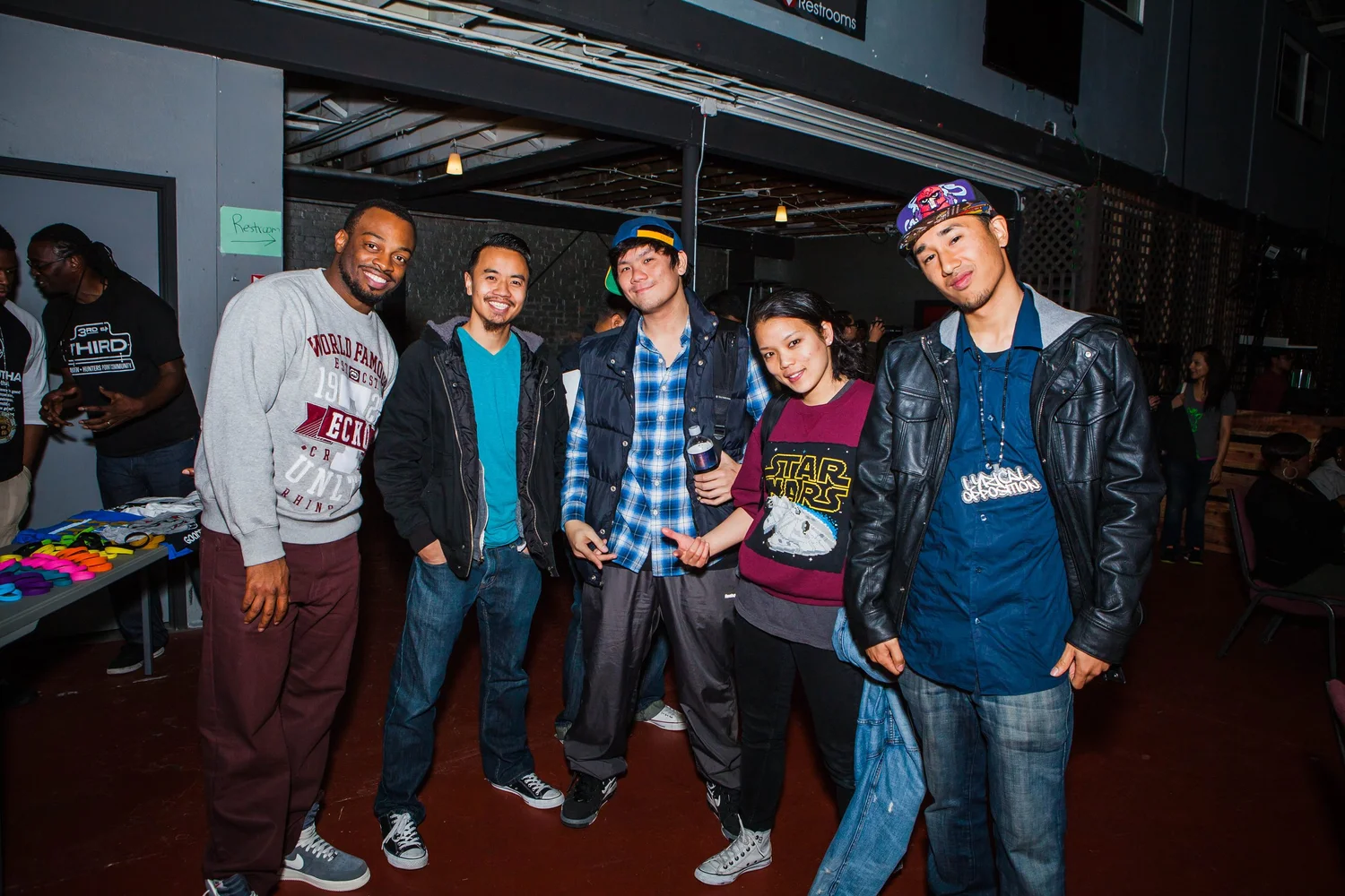 Five attendees posing beside a merchandise table.