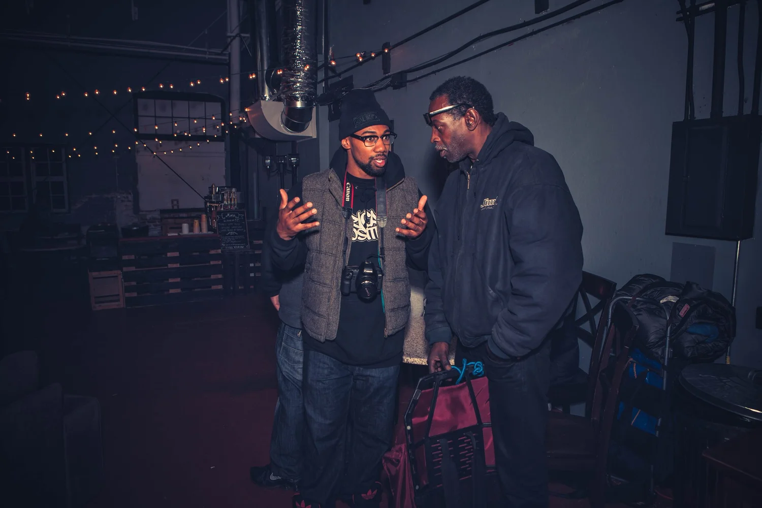 Two attendees talking beside sound equipment.