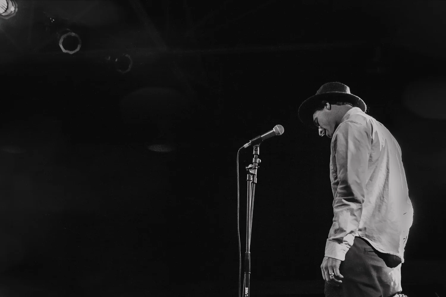 Black-and-white photo of a performer beside a microphone stand.