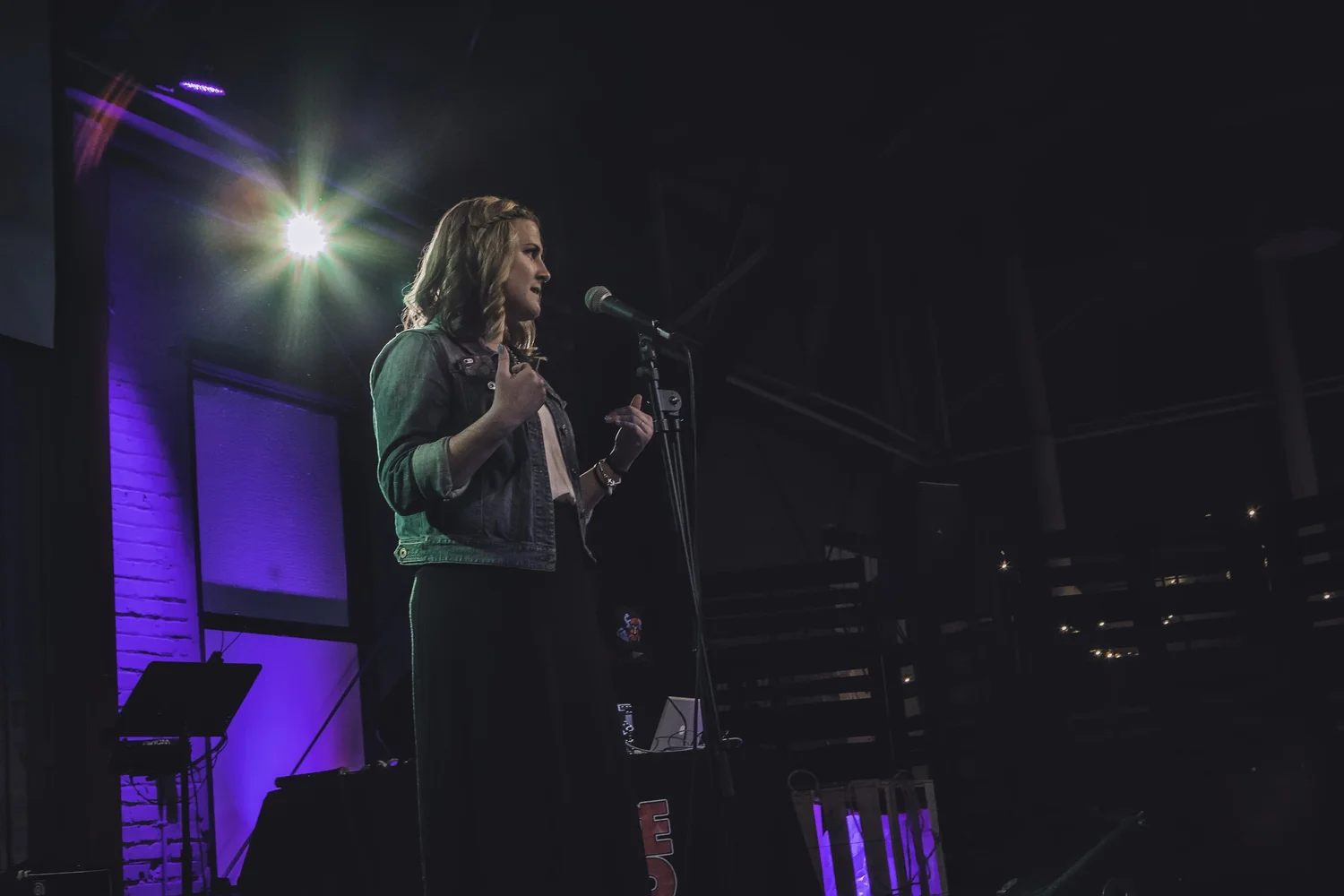 Vocalist performing at a microphone under stage lights.