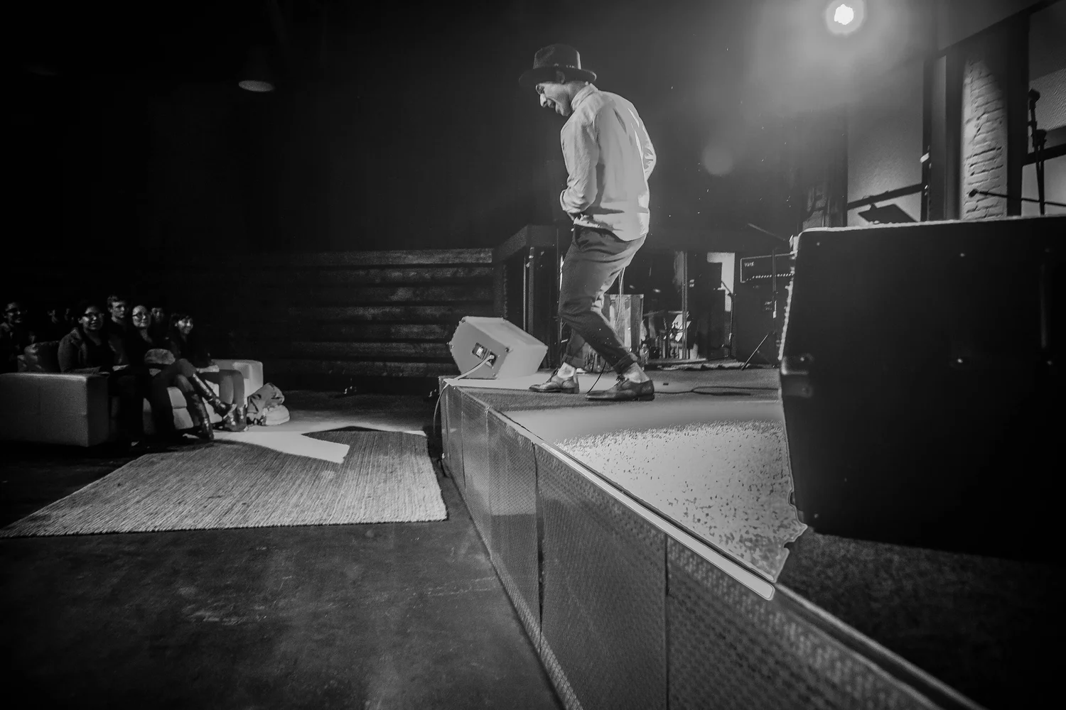 Black-and-white photo of a performer stepping across the stage.