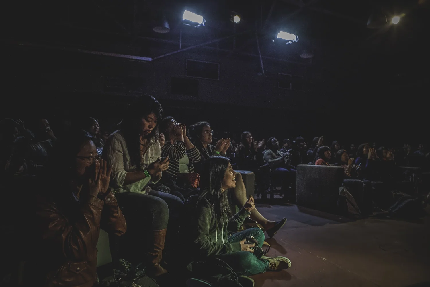 Audience members seated and standing near the stage.