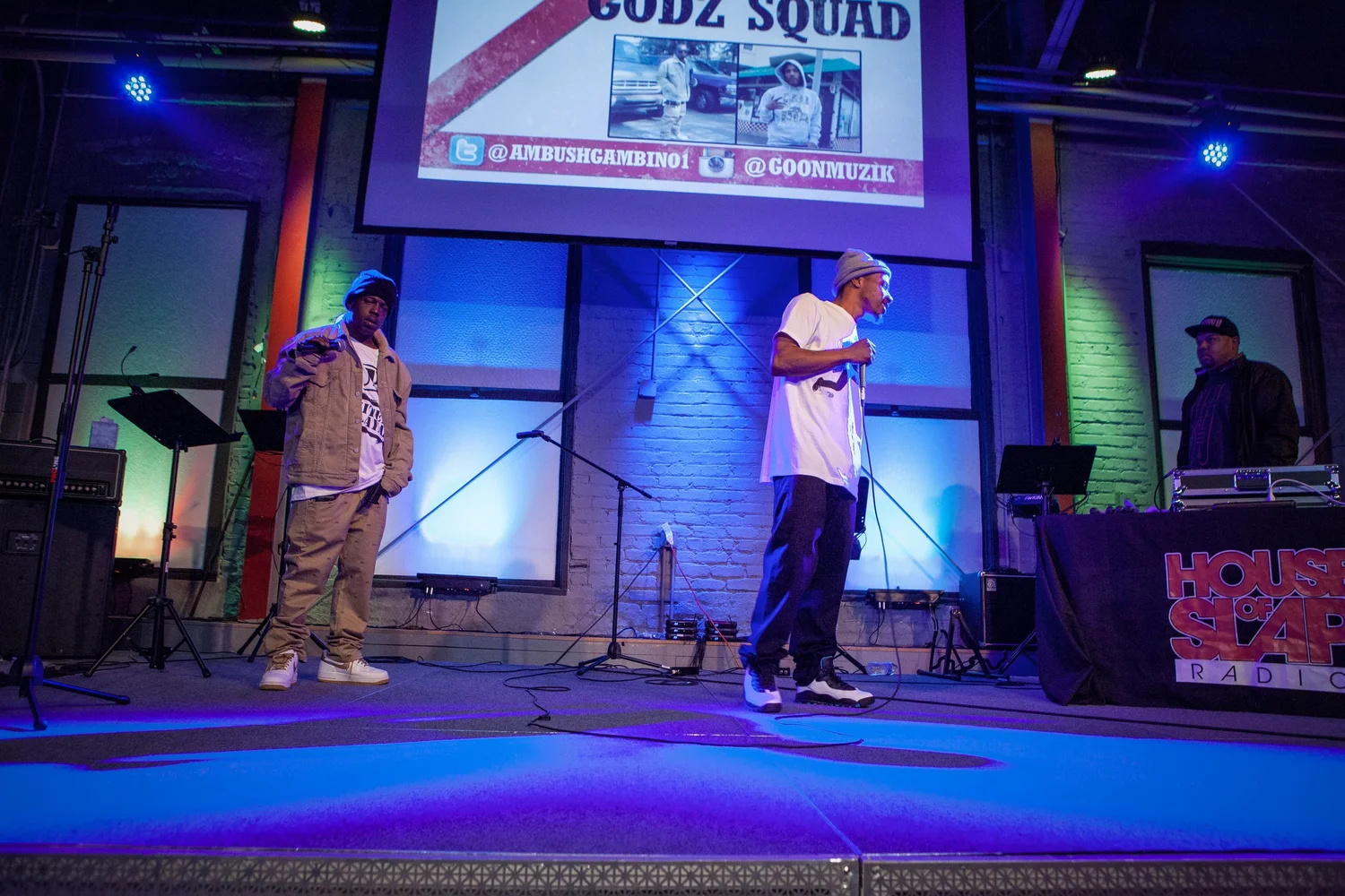 Two performers beneath a Godz Squad projection.
