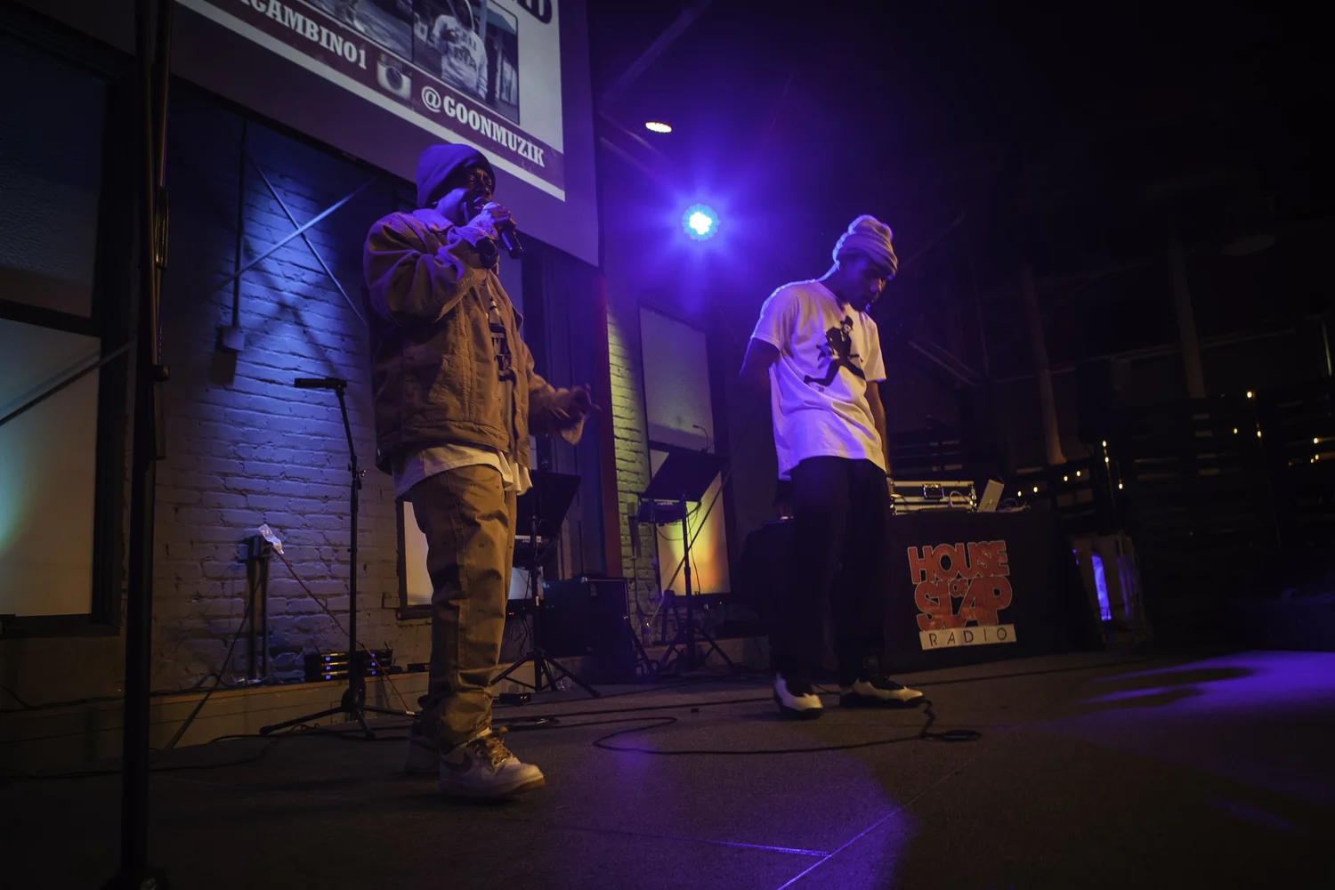Two vocalists sharing the stage under purple lights.