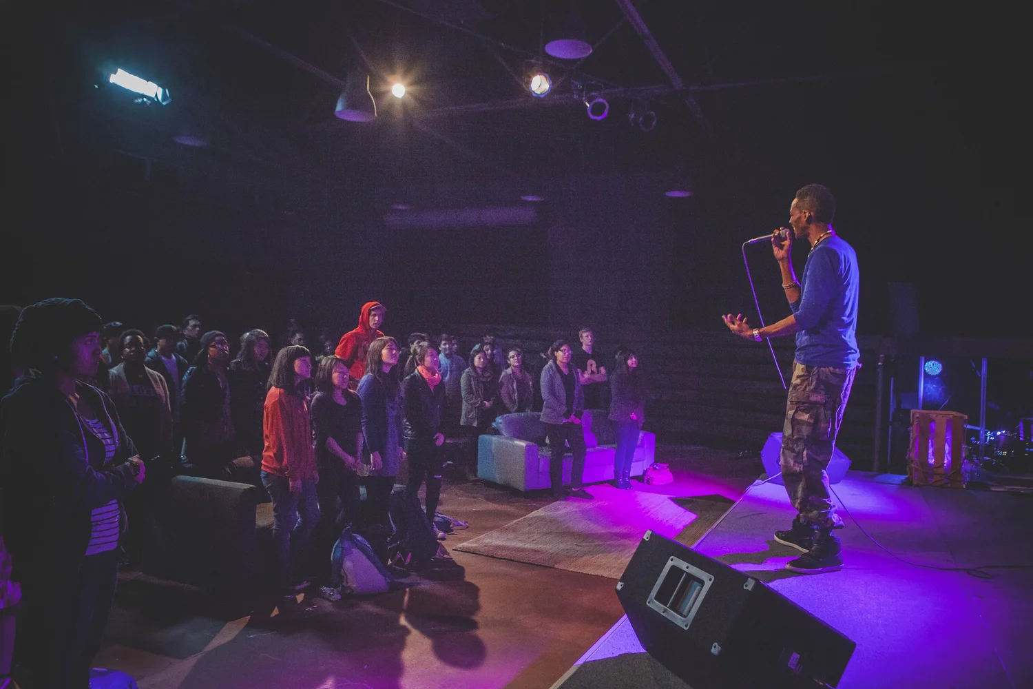 Side view of a performer facing a standing audience.