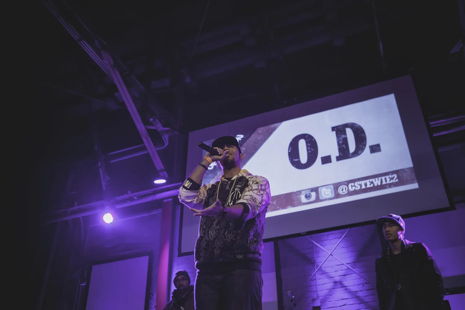 Vocalist beneath an O.D. projection.