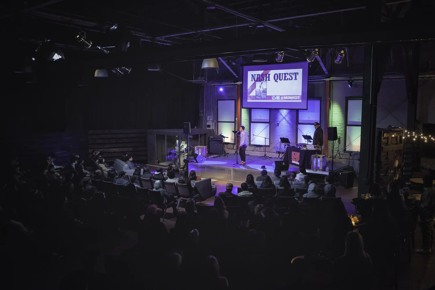 Wide view of the stage beneath a Nash Quest projection.