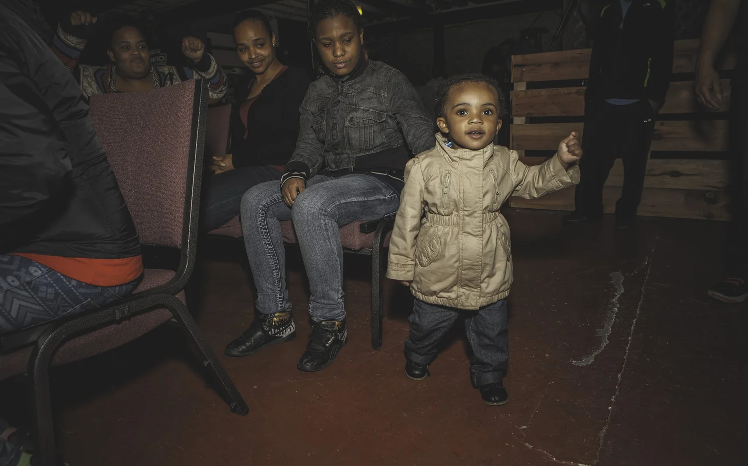 Young child standing in front of seated attendees.