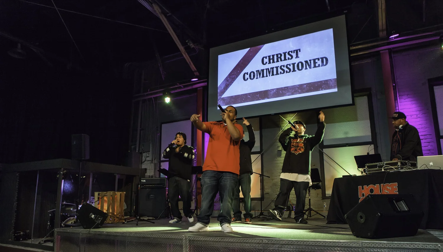 Group performing beneath a Christ Commissioned projection.